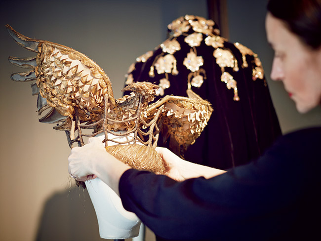 Clark adjusts an eagle headdress attributed to Jean Cocteau, circa 1938, with a rare embroidered velvet Elsa Schiaparelli evening cape, 1935–’38, in the background.